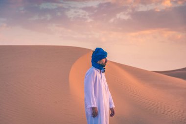 Şafak vakti Sahra Çölü 'nde geleneksel Tuareg giysileri giyen Berber adam, Merzouga, Fas
