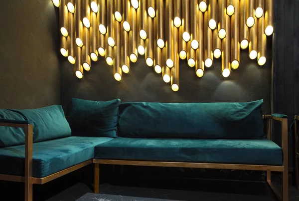 Modern lounge bar interior.Dark tone.Dark cyan sofa .Golden laterns in form of tubes.