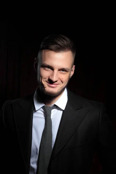 Elegant young fashion man in tuxedo smile looking at the camera.on black background.