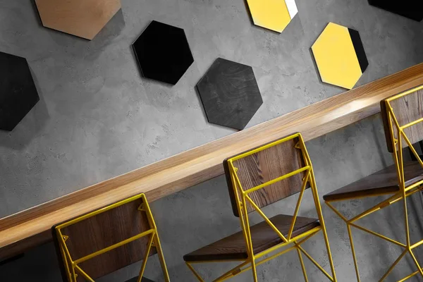 Маскировка стульев в интерьере кафе. Лофт дизайн пространства, деревянный стол, бетонная стена. креативный минималистичный интерьер кафе, простота и геометрическая концепция, черные и желтые цвета. — стоковое фото