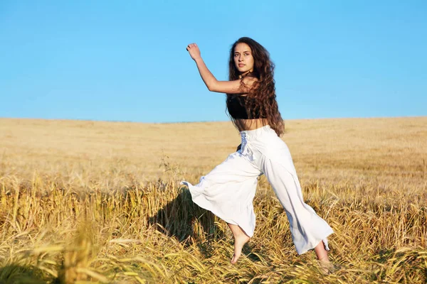 A menina bonita com cabelo longo em calças brancas elegantes e top preto Menina elegante em rye.Long cabelo, menina cacheada.Fotos de verão de uma menina bonita no field.Dynamic photo.Run — Fotografia de Stock