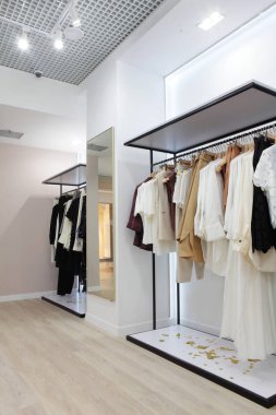 Giyim mağazasının iç . Parlak iç mekan. Minimalist tarz. Kıyafetler askıda asılı. Modaya uygun renkler