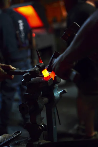 Primer plano forjando metal caliente. Con varios martillo.Varios herreros. Metal en abrazadera. Foto herrero Athmospheric. Fondo —  Fotos de Stock