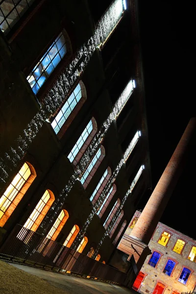 Facade with big windows building of the factory.Color window.Night shot.Perspective