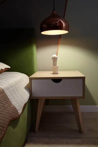 Bedroom lamp on a night table near sleeping bed.Dark room.
