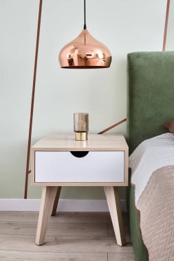 Uyku yatağının yanındaki komodinin yanında modern metal yatak odası lambası.