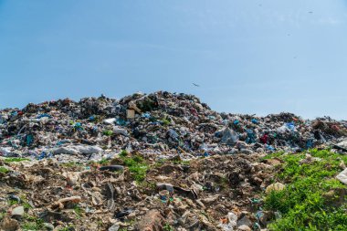 Dağlar dolusu çöp, plastik atıklar ve açık mavi gökyüzü altında reddedilen dev bir açık arazi alanı. Çevre kirliliği.