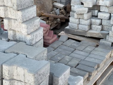 Gri ve kırmızı beton kaldırım taşları ve tuğlalar ahşap paletlere istiflenmiş. Yol ve yollar inşa etmek için inşaat malzemeleri..