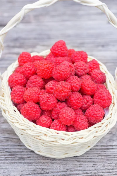 Red raspberries. Raspberries in basket on the table. Ripe berry in wicker basket. Vintage basket with raspberries.