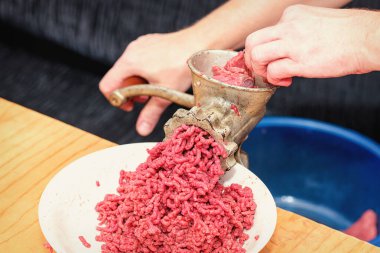 Şef taze etten doğranmış et hazırlıyor, dükkanın arka planı. Kıymalı et. Kadının elleri, kıyma makinesinin içinden kıyma çıkan manuel kıyma makinesini büker. Kıyma kıymalı kıyma elle öğütülmüş et öğütücüsünden geçer.. 