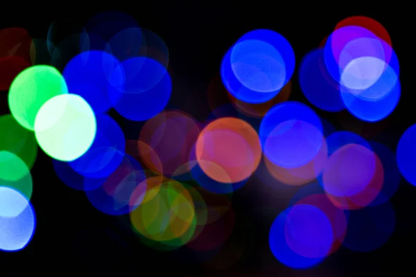 Bokeh colorful multi-colored lights yellow red blue green. Blurry lights Christmas mood. Lights from Christmas garlands defocused in beautiful bokeh. Copy space on background of multi-colored flashlights in blurry focus.