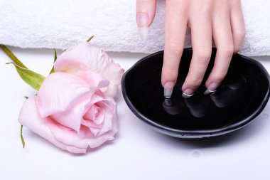 El tırnakları için kaplıca tedavisi. Kaplıca salonundaki çiviler için kozmetik prosedürler. Parmaklar pembe su banyosuna batırılmış. Rose, su penceresinin yanında, kadının elini indirdiği masada yatıyor..