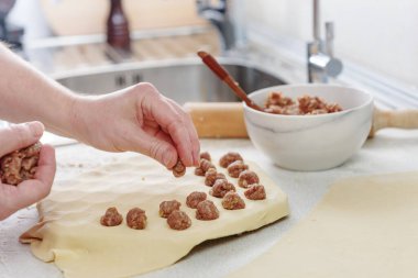 Kıymalı hamur köfteleri mutfakta pişiyor. Ev yapımı etli börek. Hamur köftesi heykeli. Masaya un serpiştirilmiş ev yapımı börekler koyun..