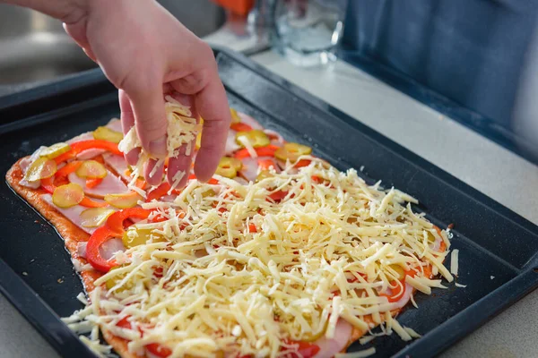 Cook prepares pizza. Cheese pizza in Italian. Cook sprinkles cheese pizza. Cooking a delicious meal of flour and cheese.