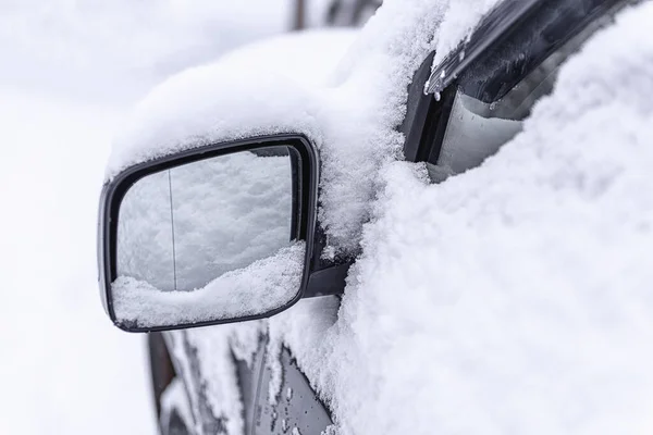 Car mirror in the snow close-up. Side mirror of car. Car standing in snow. Snowdrift snow by car. Snow covered car. Winter, snow, car in snowdrift.