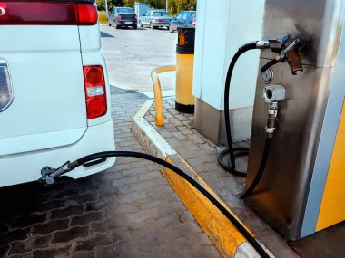 Benzin istasyonunda, beyaz araba arkasında vidalanan tankerin tabancasıyla sıvılaştırılmış benzinle tıkandı..