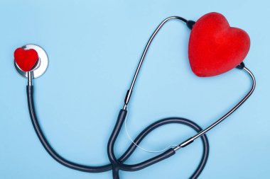 Küresel sağlık konsepti. Mavi arka planda kalbi olan şık bir doktor. Kırmızı kalbi ve mavi arka planda steteskopu yakın plan. Statoskopla kalbi dinle..