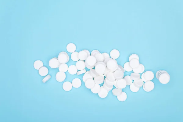 White pills on blue background.Background of large white tablets on blue paper. Pile of pills.