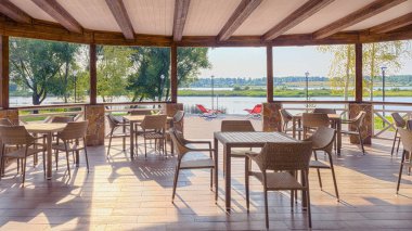 Hasırlı restoran, güzel mobilyalar nehrin kıyısında, sıcak güneş ışığıyla aydınlatılıyor..