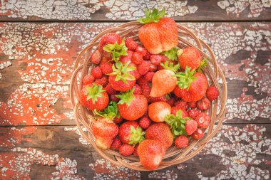 Olgun, sulu ve kırmızı, yakın planda, ahşap bir arka planda bir tabakta çilek..