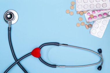 Küresel sağlık hizmeti kavramı. Kardiyovasküler hastalıkların tedavisi kavramı. Statoskop, kalp, mavi arka planda ilaç.
