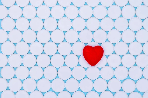 Global healthcare concept.Little red heart. Background of white pills macro with a red heart lying on the background, top view. Antibiotic resistance. Antimicrobial capsules.