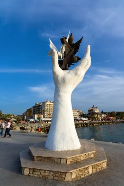 Kuşadası, Türkiye - 23 Mayıs 2015: Barış heykel Kuşadası, Türkiye'de sahildeki güvercinler ile el.