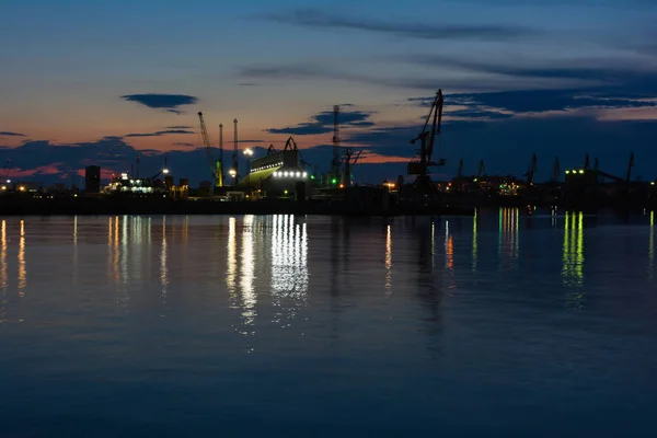 Burrgas Seehafen in der Nacht. Silhouetten von Kranichen und Spiegelungen im Wasser — Stockfoto