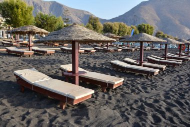 Perissa sahilinde bronzlaşma yatakları ve şemsiyeler, Santorini, Yunanistan.