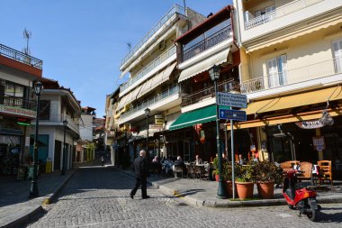 LITOCHORO, GREECE - 12 Nisan 2015: Yunanistan 'ın Litohoro köyünün merkezinde insanlar açık havada kahve içiyorlar.