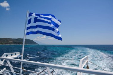 Yunanistan 'ın Ouranoupolis limanından Yunanistan' ın Halkidiki limanına giden Athos Dağı Manastırı boyunca seyahat eden bir yolcu gemisinde Yunan bayrağı.