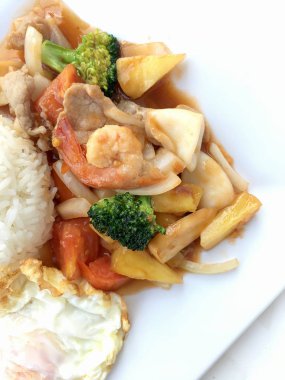 Renkli Fried karıştırın tatlı ve ekşi soslu sebze, karides ve domuz eti, meyve ve sebze beyaz arka plan üzerinde beyaz tabak içinde bir arada. Tay tarzında gıda.