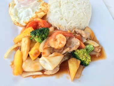 Renkli Fried karıştırın tatlı ve ekşi soslu sebze, karides ve domuz eti, meyve ve sebze beyaz arka plan üzerinde beyaz tabak içinde bir arada. Tay tarzında gıda.