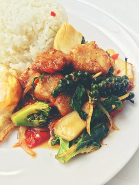 Baharatlı karıştırın kızarmış balık fileto pirinç ve beyaz arka plan üzerinde beyaz tabak kızarmış yumurta ile Tay ot ile. Vintage rengi.