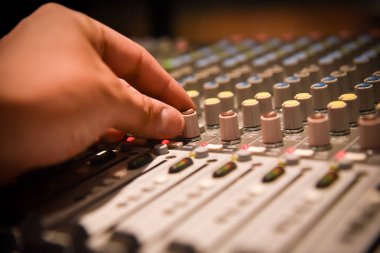yakın çekim elleri ses mühendisi ses karıştırıcı denetleyicisi canlı müzik ve stüdyo donanımları için ayarlama. Bu uzmanları için bir kalite ses sistemi var. kontrol odasında Vintage sesi ve etkisi ışık.