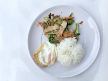 Kavrulmuş Chili Yapıştır ve karışık sebze soslu kızarmış gevrek domuz eti ilave edin; fesleğen; Kale; brokoli; havuç; kırmızı biber ve sahanda yumurta beyaz arka plan üzerinde beyaz tabak içinde Tayland Yasemin pirinç ile. Tay tarzında gıda.