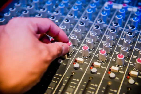 close-up hands of sound engineer adjusting audio mixer controller for live music and studio equipment. This is a quality audio system for professionals. vintage tone & effect light in control room.