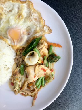 Kızarmış baharatlı deniz ürünleri fesleğen yaprakları ve karışık sebze ve pirinç yasemin beyaz tabak kızarmış yumurta ile kızarmış. Tay tarzında gıda.