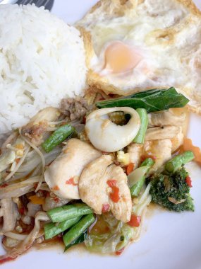 Kızarmış baharatlı deniz ürünleri fesleğen yaprakları ve karışık sebze ve pirinç yasemin beyaz tabak kızarmış yumurta ile kızarmış. Tay tarzında gıda.