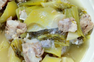 Yedek ripleri ve içinde ahşap masa üzerinde beyaz darbe çizgili domuz eti ile turşu marul çorbası. Tay geleneksel yerel Kuzey gıda.