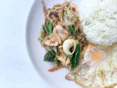 Kızarmış baharatlı deniz ürünleri fesleğen yaprakları ve karışık sebze ve pirinç yasemin beyaz tabak kızarmış yumurta ile kızarmış. Tay tarzında gıda.