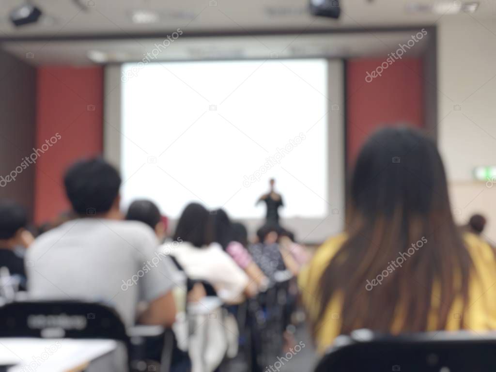 Education concept, Abstract blurred background image of students and business people  studying and discuss in large hall profession seminar with screen and projector for showing information.