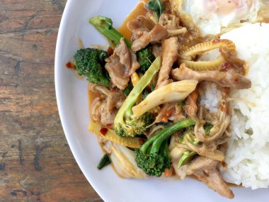 Asya tarzı tavada et dilimleri pilav ve kızarmış yumurta beyaz tabak ahşap masa üzerinde yerleştirilen Tay tarzında taze sebze ile.