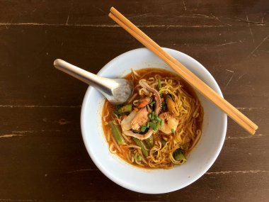 Karides, kalamar ve kabuklu deniz ürünleri ahşap masa, Tom Yum Goong üzerinde beyaz kase lezzetli Asya baharatlı deniz ürünleri şehriye çorbası. Tay tarzı yiyecek. Vintage tonu renk filtresi.