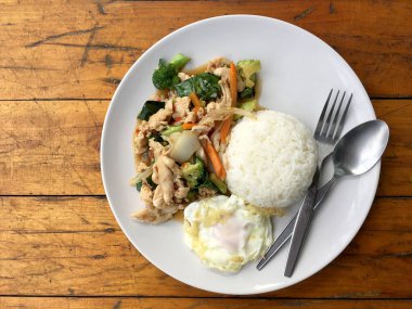 karışık sebze ve pirinç eski ahşap masa üzerinde beyaz tabak içinde Tay tarzında kızarmış yumurta ile tavada kızartılmış tavuk. Asya Tayland gıda.