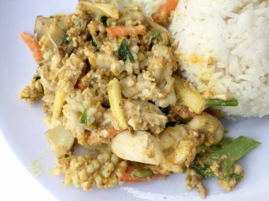 Deniz ürünleri, karides ve sarı toz köri pirinç ve kızarmış yumurta beyaz arka plan üzerinde beyaz tabakta kalamar tavada kızartılmış. Tay tarzında gıda.