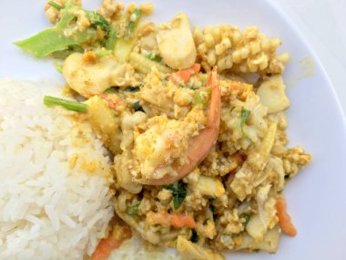 Deniz ürünleri, karides ve sarı toz köri pirinç ve kızarmış yumurta beyaz arka plan üzerinde beyaz tabakta kalamar tavada kızartılmış. Tay tarzında gıda.