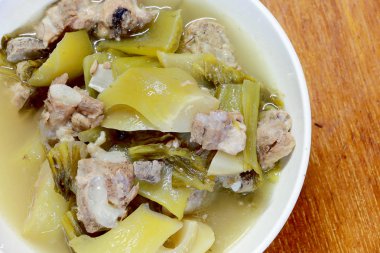 Yedek ripleri ve içinde ahşap masa üzerinde beyaz darbe çizgili domuz eti ile turşu marul çorbası. Tay geleneksel yerel Kuzey gıda.