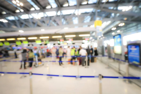 Blurred image of airport check-in counters with passengers and crowd of people control barriers with bokeh in international airport, que, travel, tourism, business concept Abstract Blur Background.