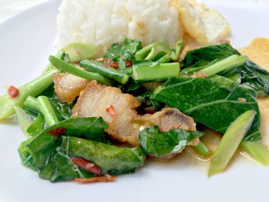 Fry stir Kai arazi ve gevrek domuz eti, beyaz arka plan üzerinde beyaz tabak kızarmış pilav pilav ile karıştırın. Tay tarzında gıda.